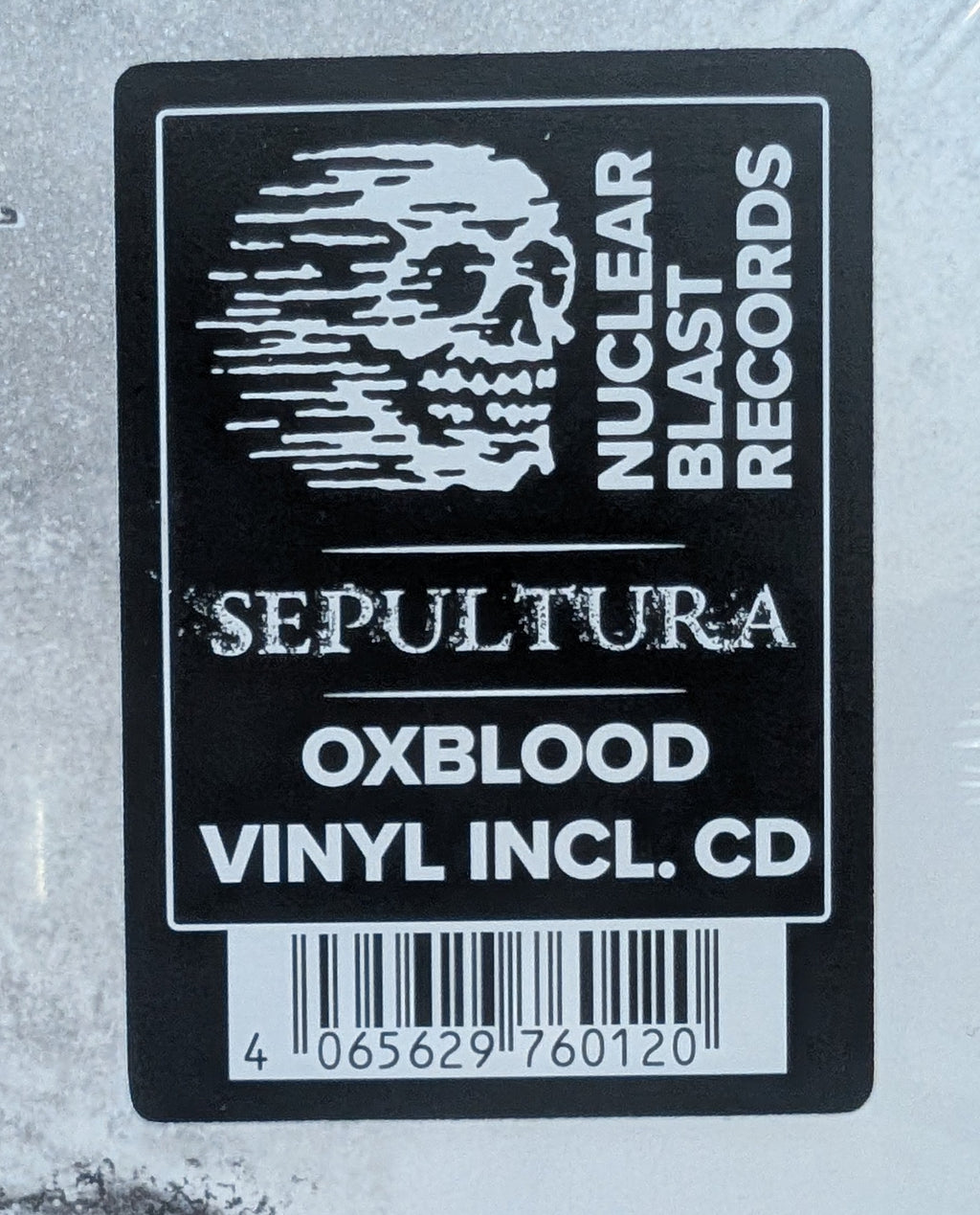 A sealed vinyl record package photographed from above on a light wood surface. The product appears to be a black-and-white album cover or CD case with a large black rectangular label reading 'SEPTITURA', 'OXBLOOD', 'VINYL INCL.