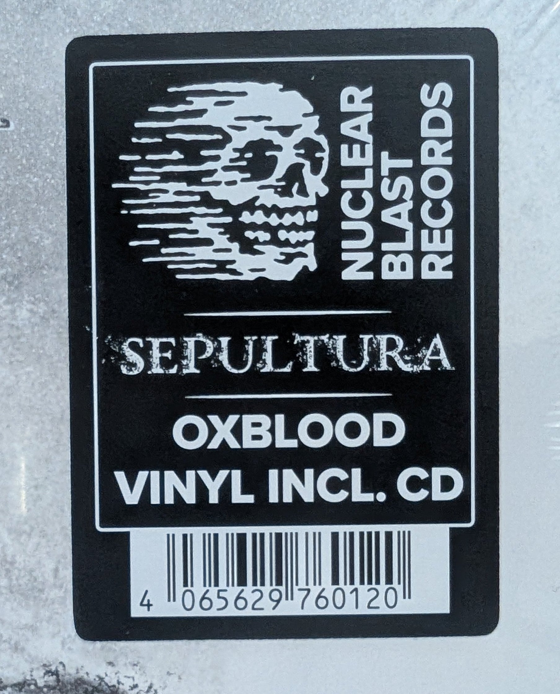 A sealed vinyl record package photographed from above on a light wood surface. The product appears to be a black-and-white album cover or CD case with a large black rectangular label reading 'SEPTITURA', 'OXBLOOD', 'VINYL INCL.